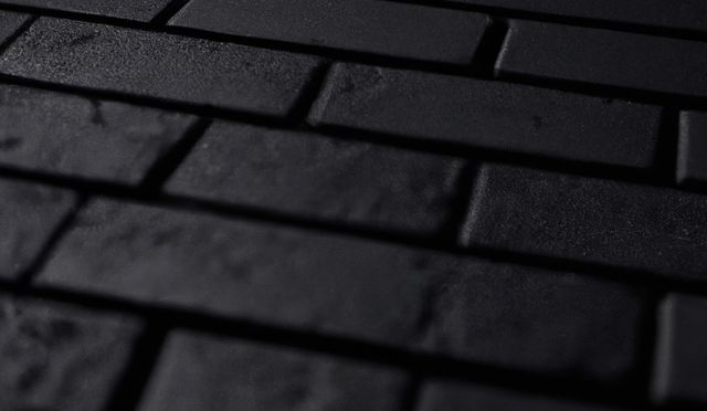Detailed close-up of a dark brick wall highlighting its texture and pattern. Perfect for backgrounds in architectural projects, construction visuals, and design themes related to urban and industrial aesthetics. Can be used for websites, advertisements, presentations, and digital artwork where a gritty, textured surface is needed.