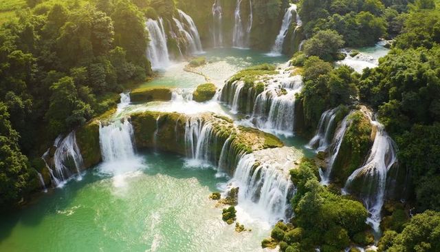 Cascading multi-tier waterfalls carving terraced rock ledges over turquoise pools