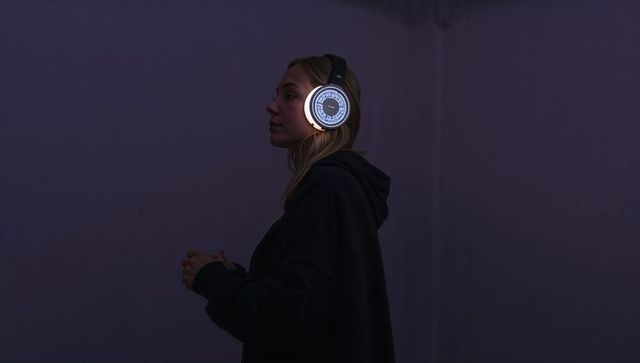Young woman wearing glowing led headphones, hoodie silhouette in moody purple neon light