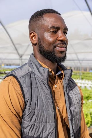 Confident Man in Eco-Friendly Greenhouse Overseeing Hydroponic Farm