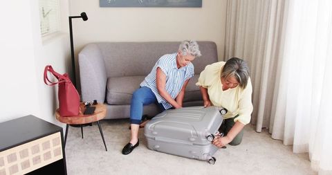 Senior Couple Packing Suitcase in Cozy Living Room for Vacation