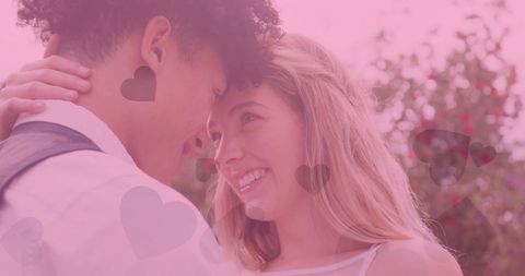 Happy Diverse Couple Embracing at Outdoor Wedding with Pink Heart Overlay