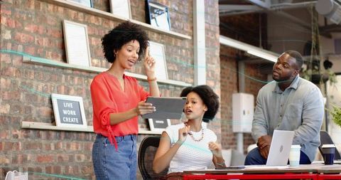 Creative team presenting tablet during brainstorming session in modern coworking space