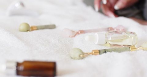 Spa skincare flatlay featuring jade and rose quartz rollers with facial oil dropper amber bottle