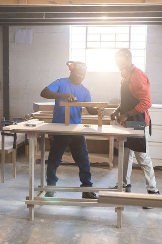 African american woodworkers collaborating on custom furniture in sunlit carpentry shop