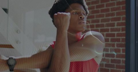 Male athlete stretching arm across chest in brick gym wearing wristwatch and red tank