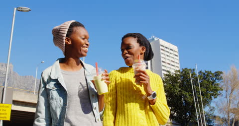 Smiling Twin Sisters Walking Together in City