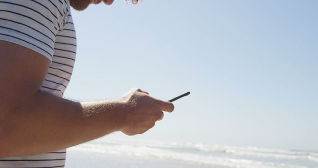 Young man using smartphone on sunny beach - Download Free Stock Images Pikwizard.com