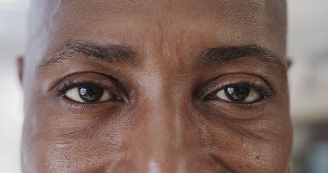 This striking image captures a detailed close-up of a man's face, focusing on his intense eyes and fearless gaze. The visible wrinkles and texture of the skin add depth and character. This can be used in contexts related to human emotions, self-confidence, and personal strength. Ideal for articles or campaigns centered around empowerment and individuality.