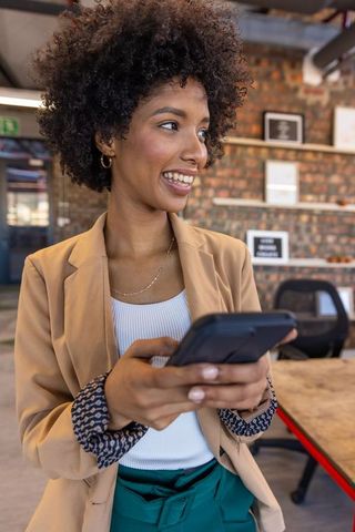 Smiling African American Businesswoman Networking Using Phone in Office