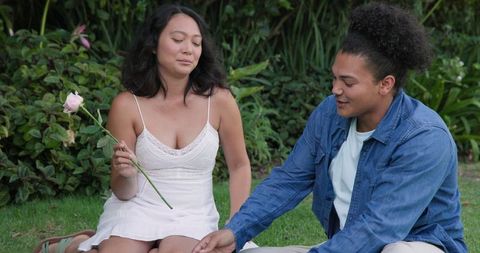 Happy Couple Enjoying Outdoor Picnic with a Rose in Hand