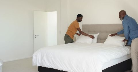 Father and Son Making Bed in Minimalist Bedroom Interior