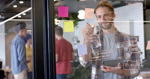 Young Professional Brainstorming on Glass Wall in Modern Office