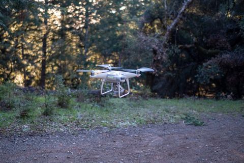 Technology drone hovering in forested scenic area at sunset
