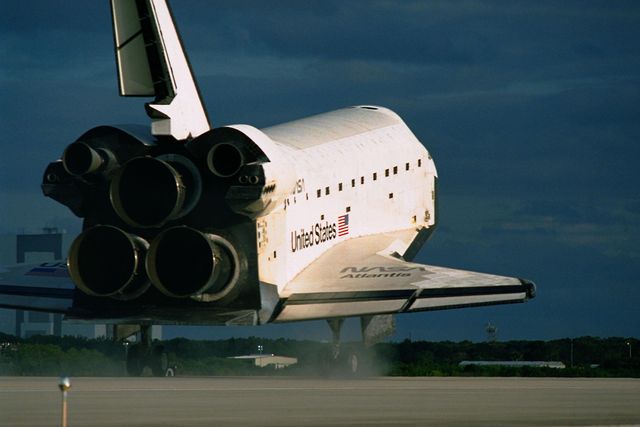 Space Shuttle Atlantis lands on Runway 15 at the Kennedy Space Center Shuttle Landing Facility after completing the 11-day STS-86 mission. This mission involved docking with the Mir Space Station and exchanging crew members. Suitable for educational material on space exploration, articles about historic NASA missions, or promotional content for science and technology exhibits.