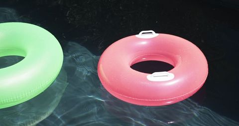 Two Vibrant Swim Rings Floating on Calm Water Surface