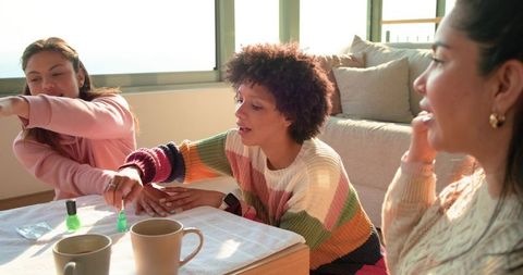Diverse friends applying bright green nail polish during cozy sunlit at-home manicure