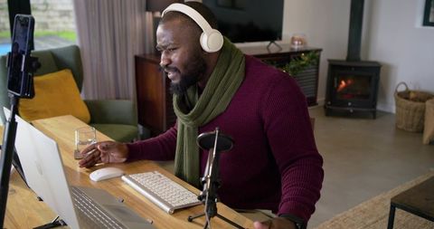 African American Podcaster Recording at Home Desk with Headphones and Microphone