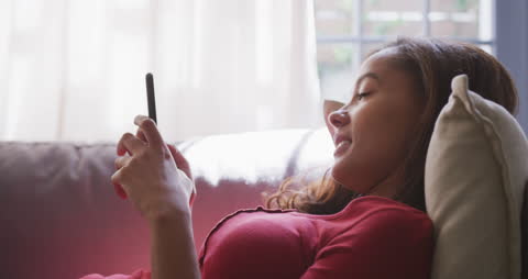 Young Woman Relaxing at Home Using Smartphone