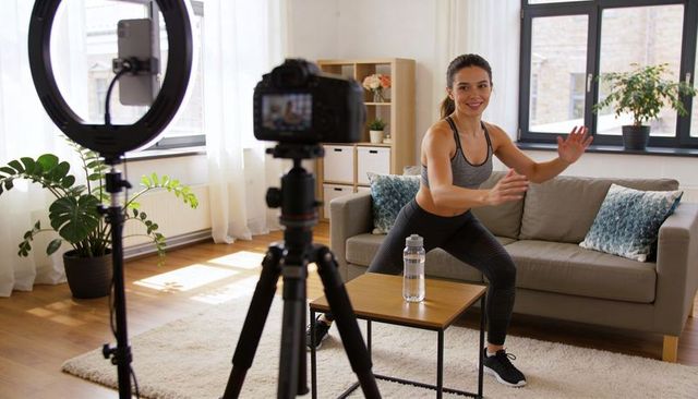 Female Trainer Recording Home Workout with Ring Light and Camera in Bright Living Room