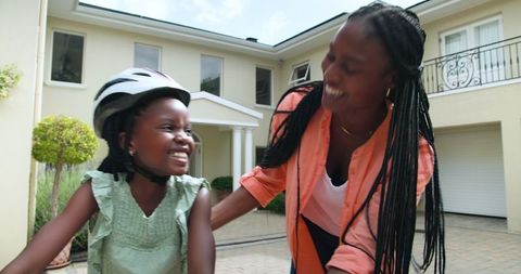 Mother Teaching Daughter to Ride Bike Smiling Outdoors