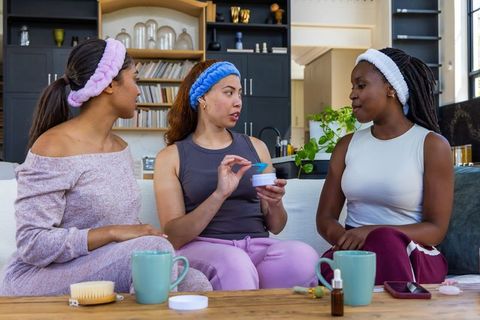 Three african women sharing skincare and self-care rituals at cozy home spa gathering