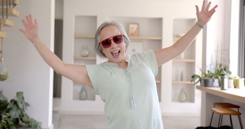Excited Elderly Woman with Sunglasses Celebrating at Home