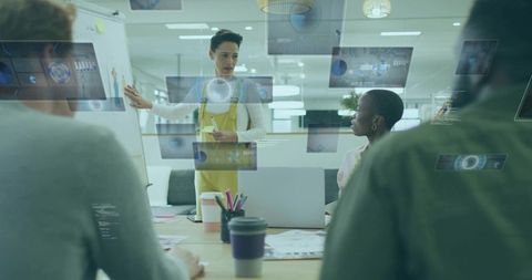 Leading woman presenting holographic UI to collaborative team in open plan office meeting