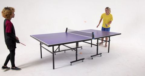 Athletic female friends competing in table tennis game
