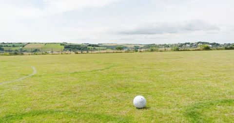 White soccer ball on grassy sports field with rural views