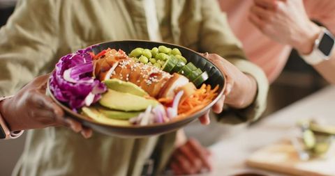 Diverse couple sharing vibrant healthy bowl with avocado edamame and sesame-coated protein