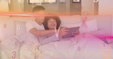 Relaxing couple sharing tablet in bed with warm ambient light and floating letter overlay