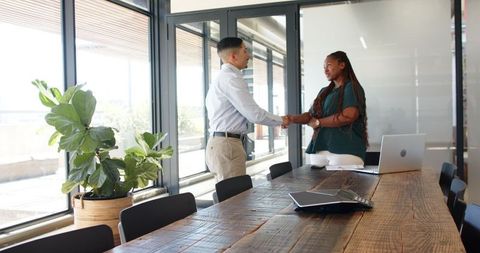 Business Professionals Shaking Hands in Modern Meeting Room