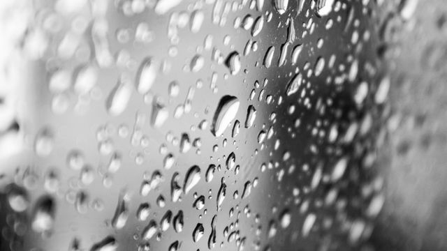 Close-up of water droplets on glass, ideal for conveying themes of freshness, nature, or humidity. It can be used to illustrate concepts in science basics, hydrology, or even metaphors highlighting clarity and purity in blogs or presentations.