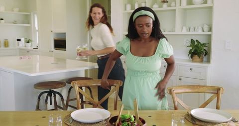 Diverse friends setting table kitchen socializing