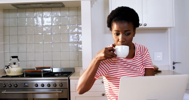 Woman Drinking Coffee While Using Laptop in Modern Kitchen - Download Free Stock Images Pikwizard.com