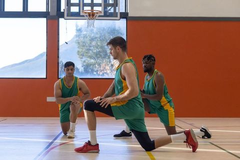 Basketball team teammates training with forward lunges in gym
