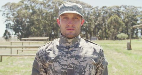 Caucasian male soldier standing confidently in field training area