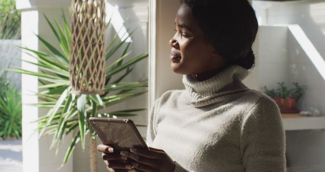 Relaxed Woman Holding Tablet and Looking Through Window at Home - Download Free Stock Images Pikwizard.com