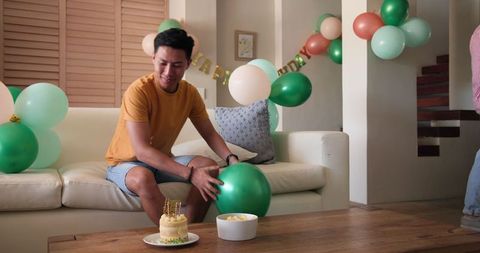 Man preparing living room with balloons for birthday celebration