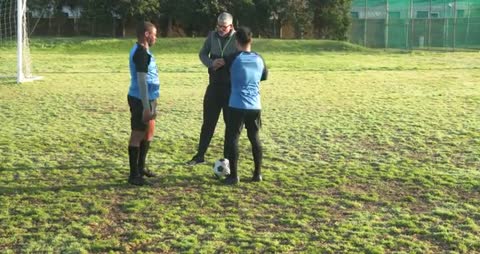 Coach Discussing Strategy with Soccer Players on Field