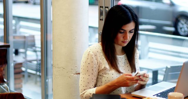 Woman Working on Laptop and Checking Smartphone in Coffee Shop - Download Free Stock Images Pikwizard.com