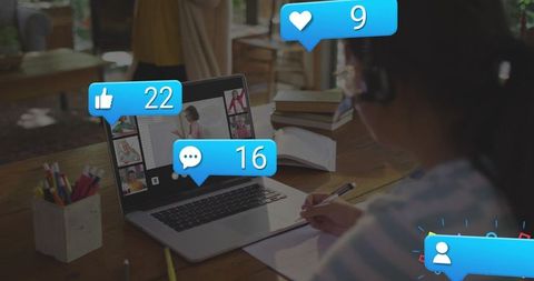 Student taking notes during online class with social reaction icons, remote learning