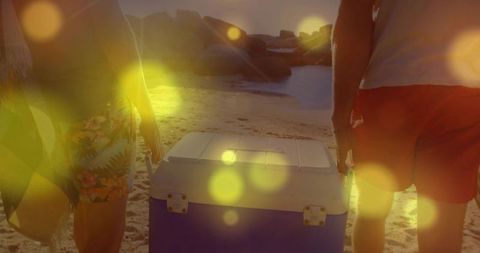 Friends walking beach with cooler during sunset adventure