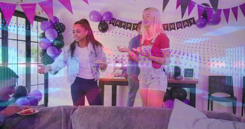 Young friends celebrating birthday with cupcakes, purple balloons and banners in living room