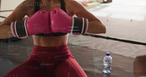 Woman boxer leaning on ropes holding pink gloves training in boxing ring