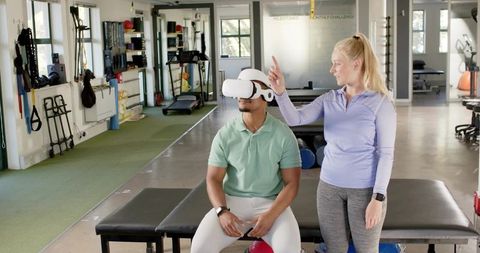 Vr-assisted rehabilitation session with trainer guiding seated client in modern clinic