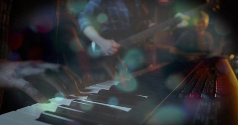 Keyboardist playing synth and guitarist performing with moody bokeh stage lights