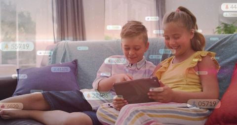 Siblings sharing tablet on sofa, laughing and tapping with social media overlays