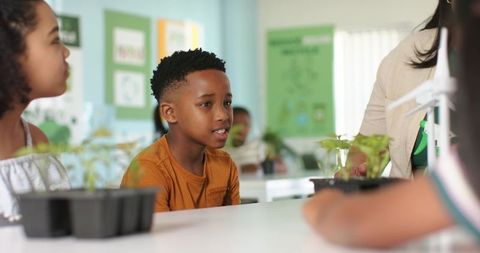 Students engaging in hands-on classroom gardening with african american boy listening